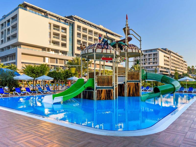 Hôtel avec piscine extérieure et toboggans pour enfants sous un ciel clair.
