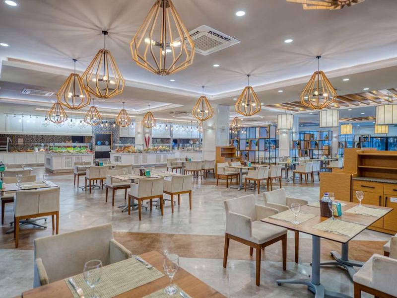 Salle à manger spacieuse et lumineuse avec éclairage moderne et plusieurs tables pour les invités.