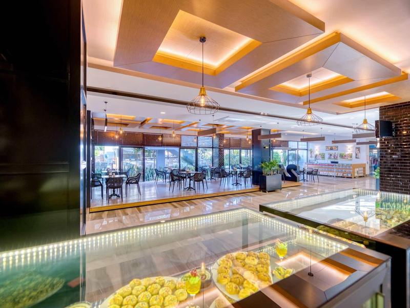 Salle à manger lumineuse avec éclairage moderne au plafond et vitrines en verre avec nourriture.