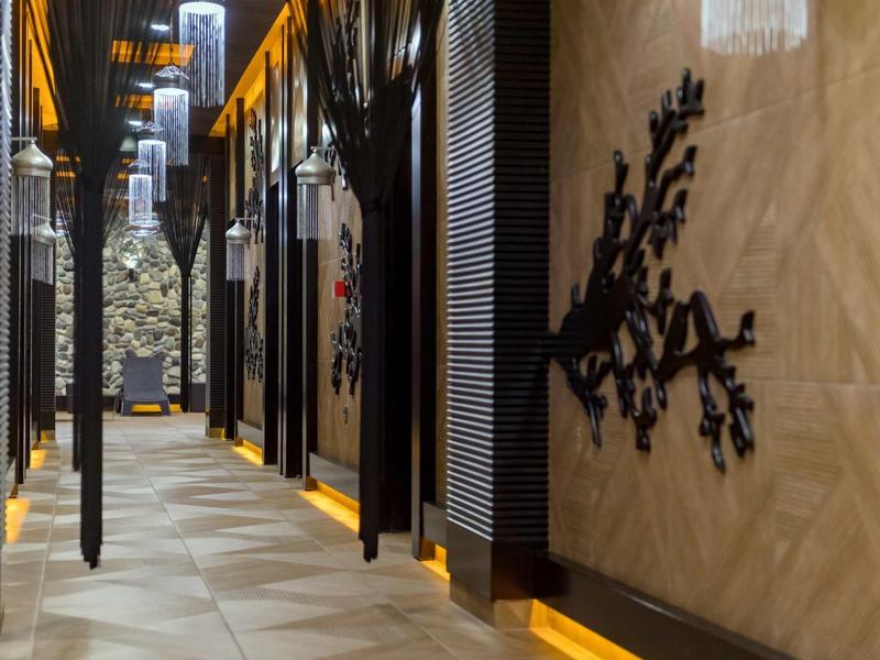 Couloir d'hôtel moderne avec lampes murales et accents muraux décoratifs sous une lumière chaude.