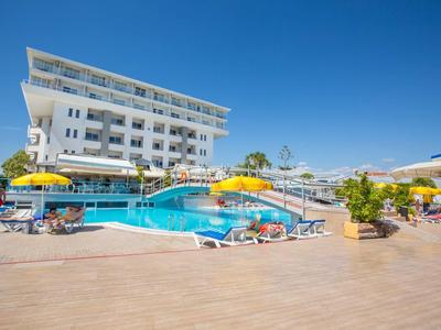 Hotel with outdoor pool, water slide, and sun umbrellas on a sunny day