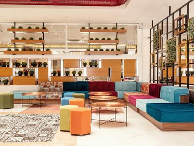 Modern hotel lounge area with colorful seating and stylish shelves on the wall.