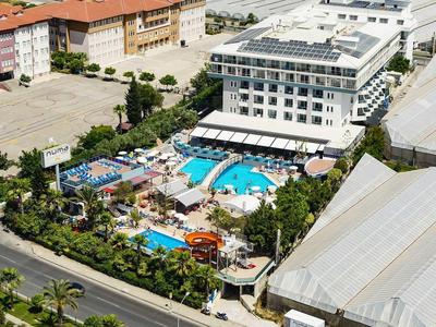 Großes Hotel mit blauem Pool, Wasserpark, umliegenden Gebäuden und grünen Bäumen.