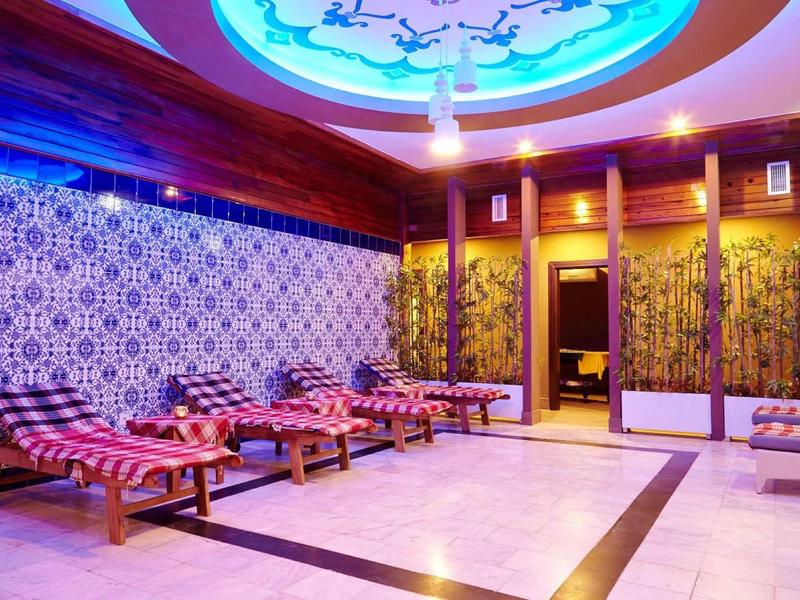 Innenraum eines Wellnessraums mit Holzliegen, gemusterter Wand und beleuchtetem Deckendekor.