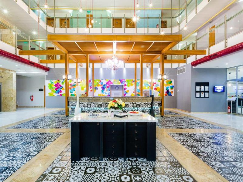 Großer, heller Innenraum mit Musterfliesen, Buffet-Tisch und bunter Kunst an der Wand.