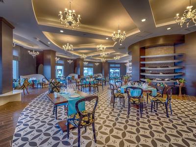 Comedor elegante con sillas coloridas, candelabros y suelo con patrón en un hotel.