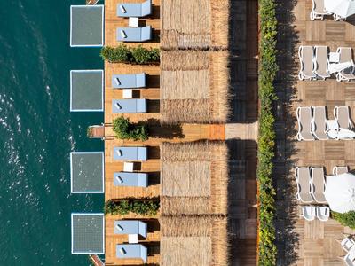 Vista aérea de tumbonas y sombrillas en la playa junto a agua azul clara.