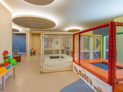 Vista interior de una moderna zona de juegos para niños en un hotel con trampolín colorido y bloques de construcción.