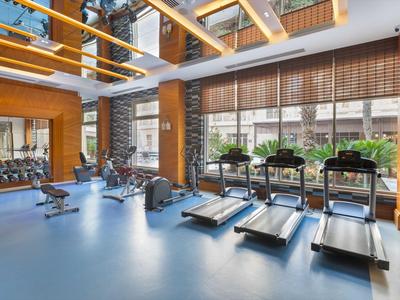 Salle de sport moderne avec tapis de course, haltères et grande fenêtre donnant sur l'extérieur.