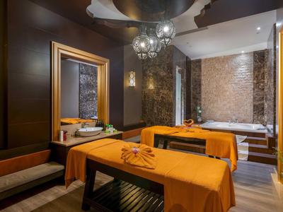 Sala de spa elegante con dos camillas de masaje, colores cálidos y luz tenue.