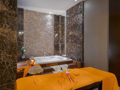 Sala de spa elegante con jacuzzi y camilla de masaje naranja en ambiente cálido y lujoso.