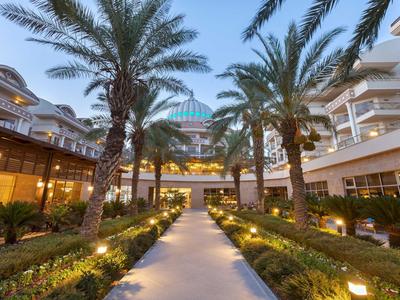 Einwegweiser Weg durch Palmen zu modernen Gebäuden mit Beleuchtung bei Abenddämmerung.