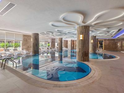 Piscina interior con columnas decorativas y asientos, en un ambiente de hotel moderno.