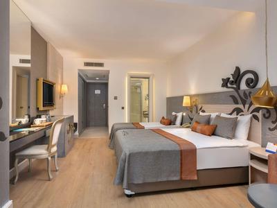 Chambre d'hôtel moderne avec lit double, bureau et sol en bois.