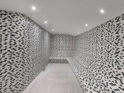 Sala moderna con paredes de mosaico blanco y negro y luces LED en el techo de un hotel.