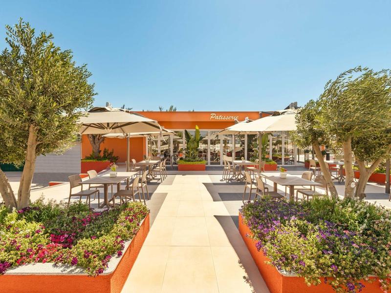 Área exterior moderna de un hotel con asientos, sombrillas y plantas.