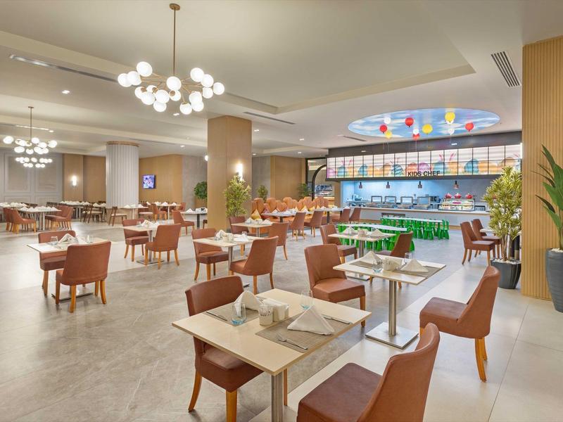 Restaurante moderno con sillas marrones, mesas blancas e interior iluminado, variedad de luces.