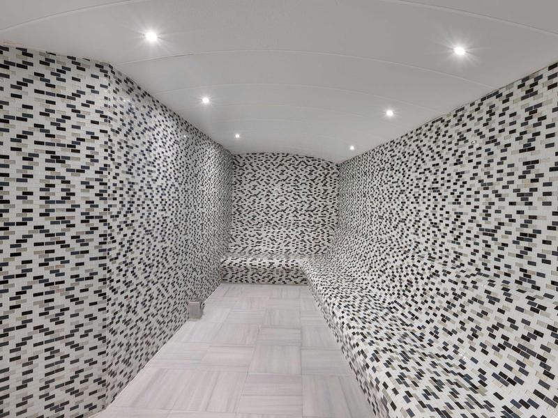 Sala moderna con paredes de mosaico blanco y negro y luces LED en el techo de un hotel.