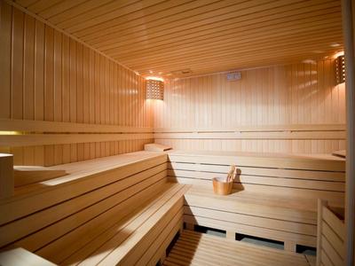 Intérieur lumineux de sauna en bois avec des bancs et un seau au centre.