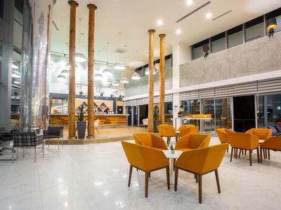 Hall d'hôtel moderne avec des fauteuils orange et un sol en marbre clair.