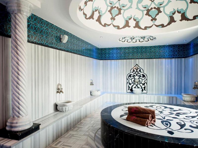 Luxury spa room with round marble tub, ornate ceiling, and elegant seating area.