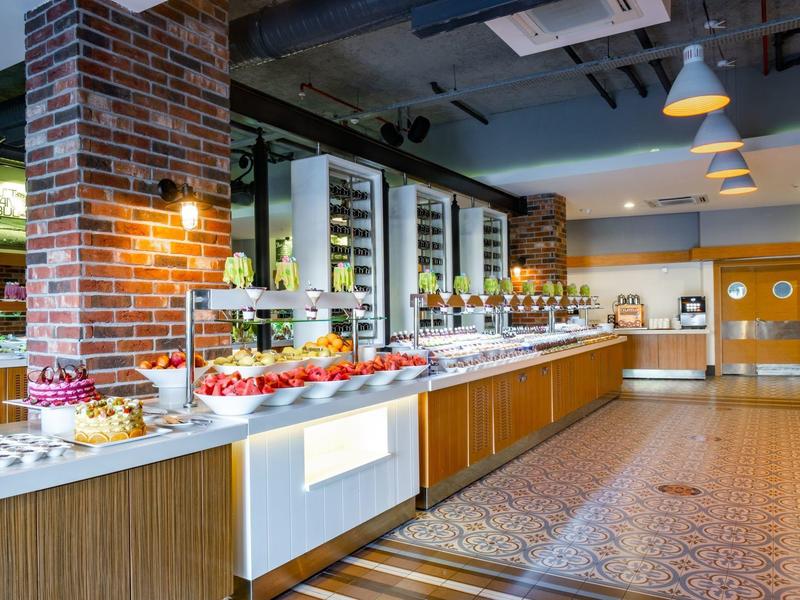 Modern buffet area with food displays and warm lighting in a spacious dining room.