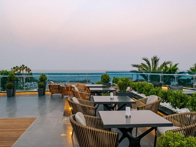 Outdoor terrace at a hotel with modern seating and ocean view at dusk.
