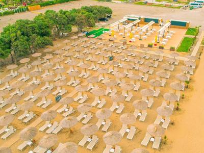 Pláž s řadami slunečníků a lehátek uspořádaných na písku.