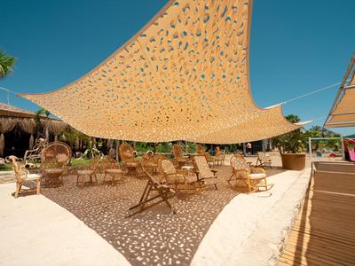 Outdoor-Sitzbereich mit Holzmöbeln unter einem Sonnensegel bei blauem Himmel