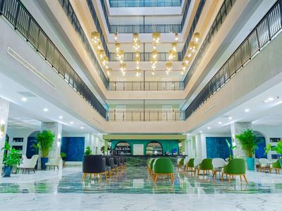 Prostorná hotelová hala s vysokými stropy, přirozeným světlem a moderním nábytkem.