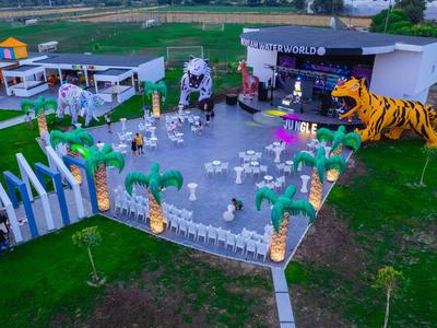 Bunte Außenbühne mit Tigerdekor und Sitzbereichen auf Rasenfläche in einem Freizeitpark