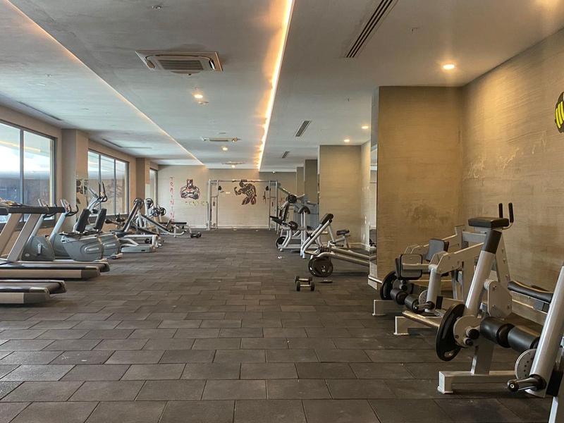 Moderní posilovna s běžeckými pásy a rotopedy, světlé zdi a velká okna.