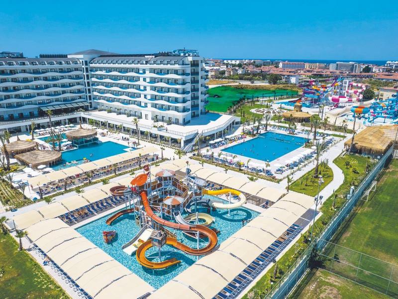 Hotel s vodními skluzavkami a bazény obklopený zelení a lehátky.