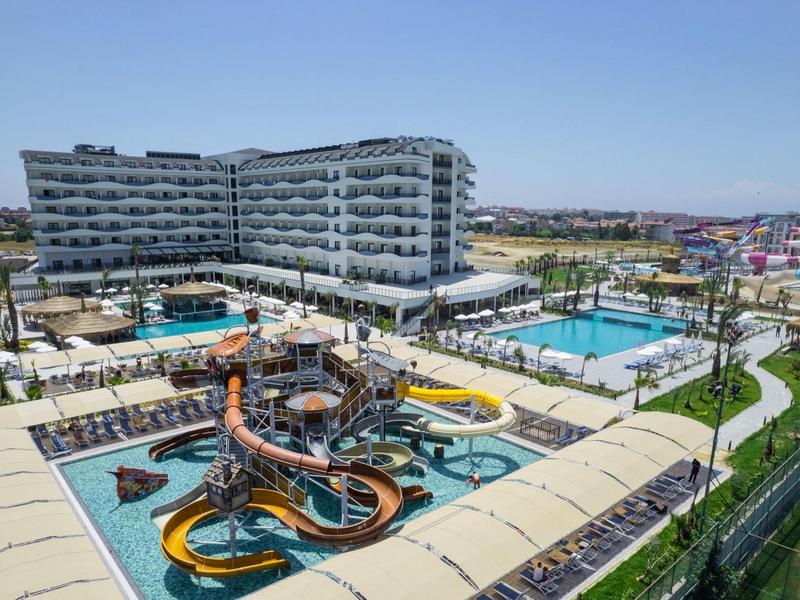 Moderní hotelový komplex s bazény, vodními skluzavkami a odpočinkovými zónami na slunci.