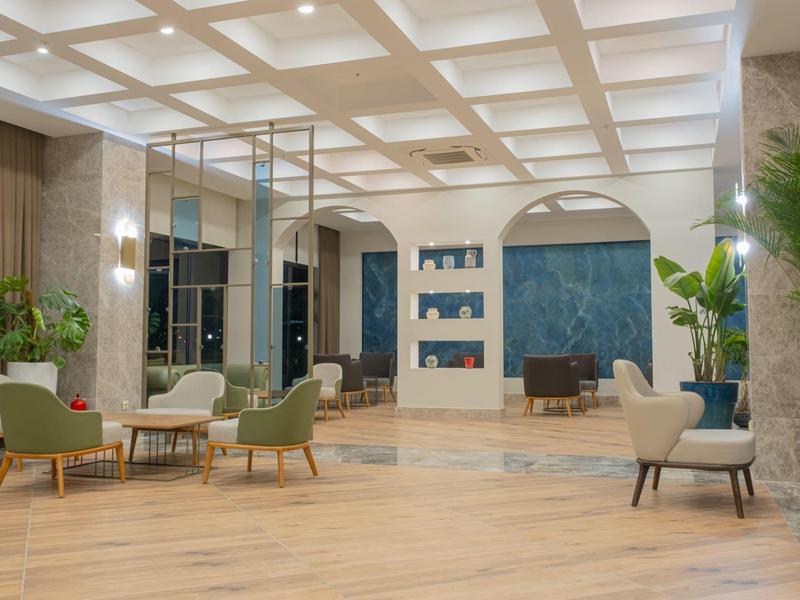 Moderní hotelová hala s pohodlným posezením a velkými zelenými rostlinami.