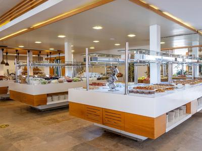 Světle osvětlený bufet restaurace s moderním designem a různými možnostmi jídla.