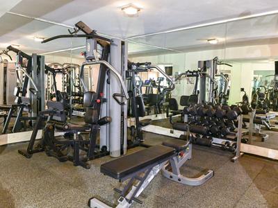 Gimnasio con varias máquinas de fuerza y pared de espejos en un hotel.