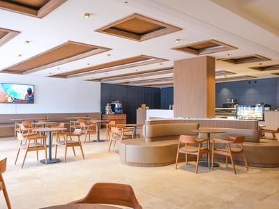 Světlá, moderní hotelová jídelna s dřevěným nábytkem a centrálním posezením.