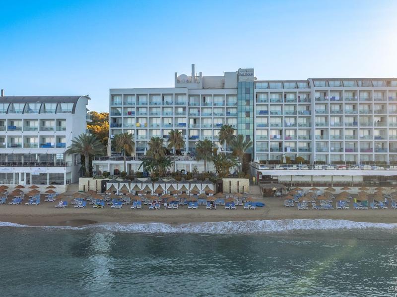 Velká vícepatrová hotelová budova na pláži pod jasnou oblohou.