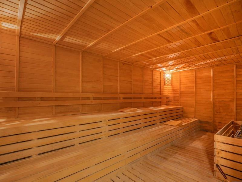 Spacious wooden sauna with multi-level benches and warm lighting.
