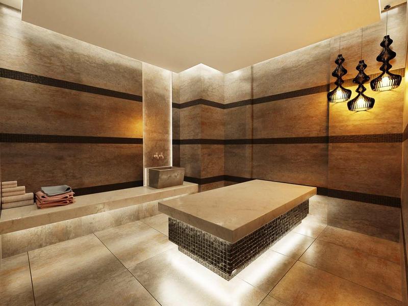 Modern steam room with stone bench, warm lighting, and decorative wall sconces in a hotel spa.