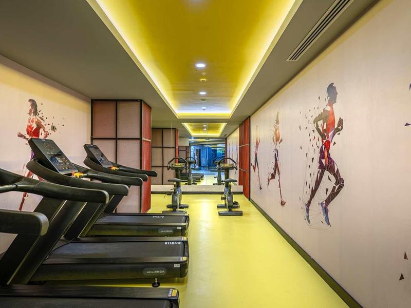 Modern gym with treadmills and fitness decor on bright yellow floor and walls.