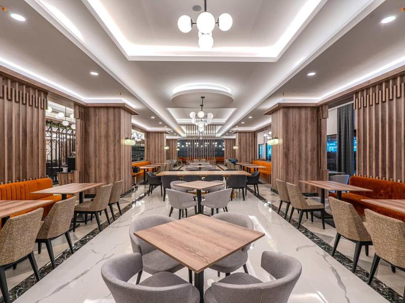 Spacious hotel dining room with modern lighting, wooden accents, and comfortable seating.