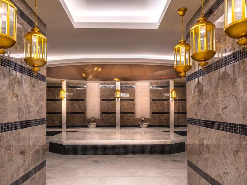 Luxurious marble spa room with multiple shower stalls and golden lantern lighting.