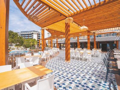 Lounge exterior cubierta con suelo de azulejos coloridos y mesas y sillas blancas