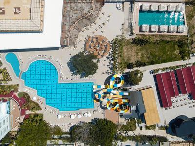 Luchtfoto van een hotelzwembad met ligstoelen en kleurrijke glijbanen.
