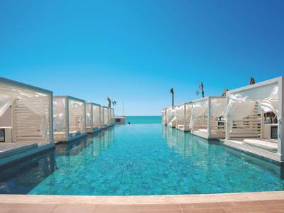 Zwembad met witte cabana's en heldere lucht met uitzicht op zee