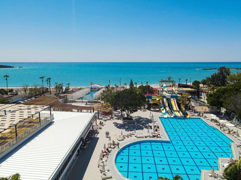 Buitenzwembad met glijbanen en zeezicht onder heldere blauwe lucht