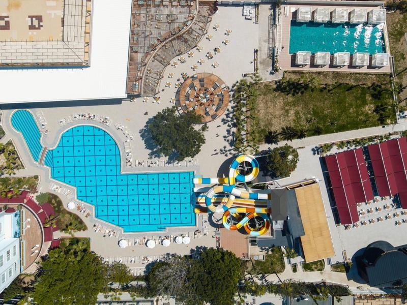 Luchtfoto van een hotelzwembad met ligstoelen en kleurrijke glijbanen.