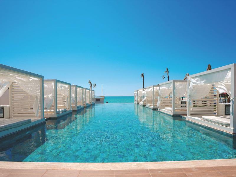 Zwembad met witte cabana's en heldere lucht met uitzicht op zee